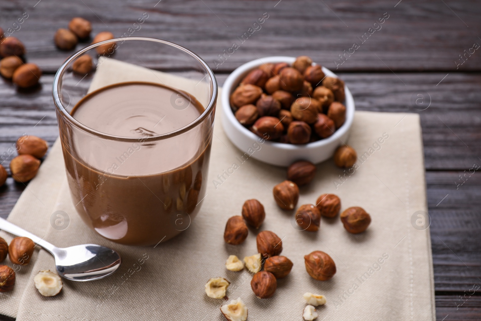 Photo of Glass with chocolate paste and nuts on wooden table. Space for text