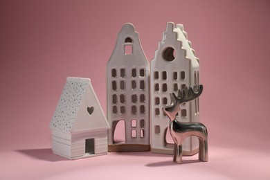 Photo of House shaped candle holders and silver deer on pink background