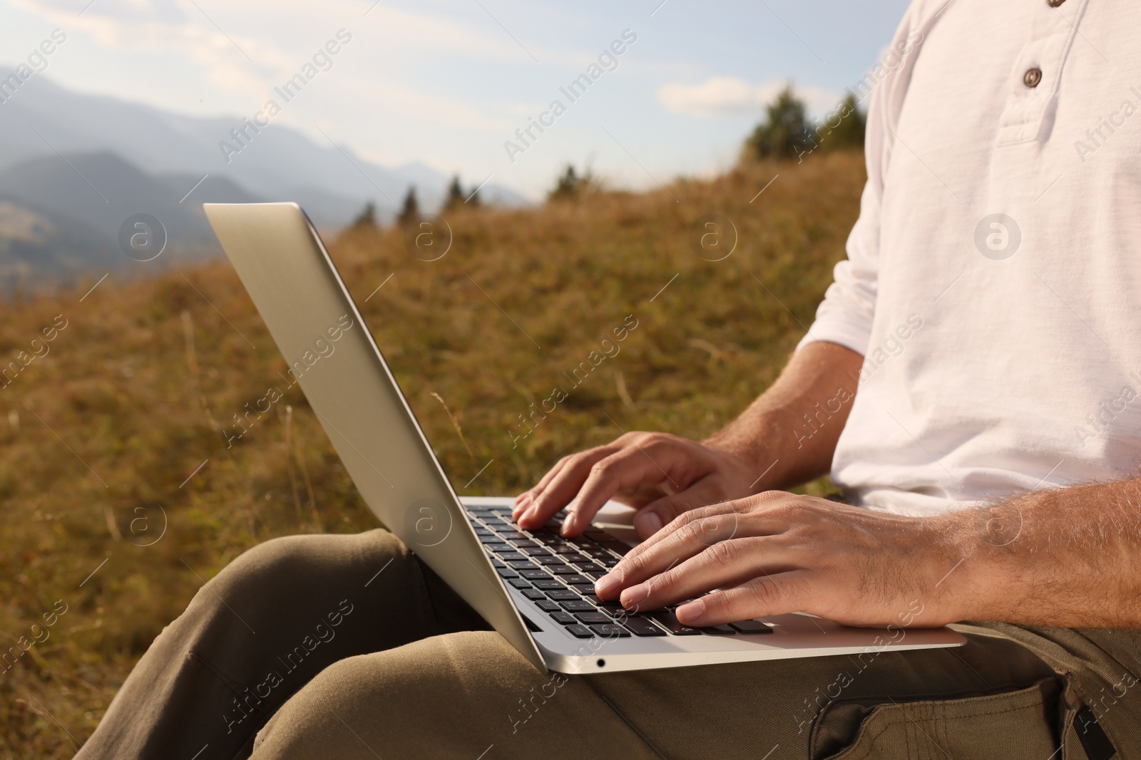 Photo of Man working with laptop outdoors on sunny day, closeup