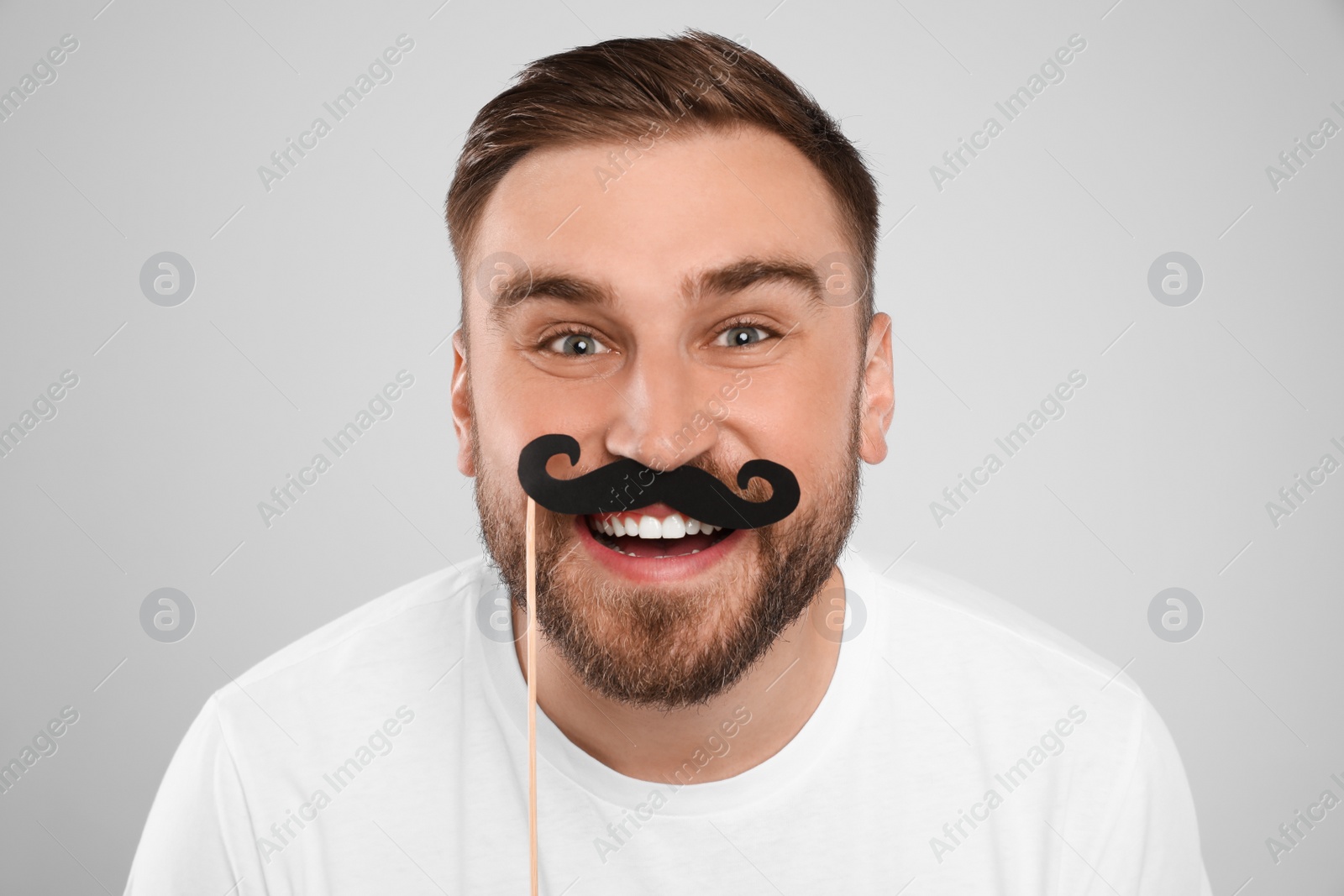 Photo of Funny man with fake mustache on light grey background