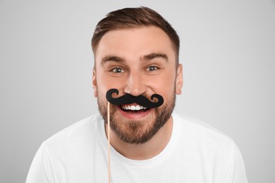 Photo of Funny man with fake mustache on light grey background