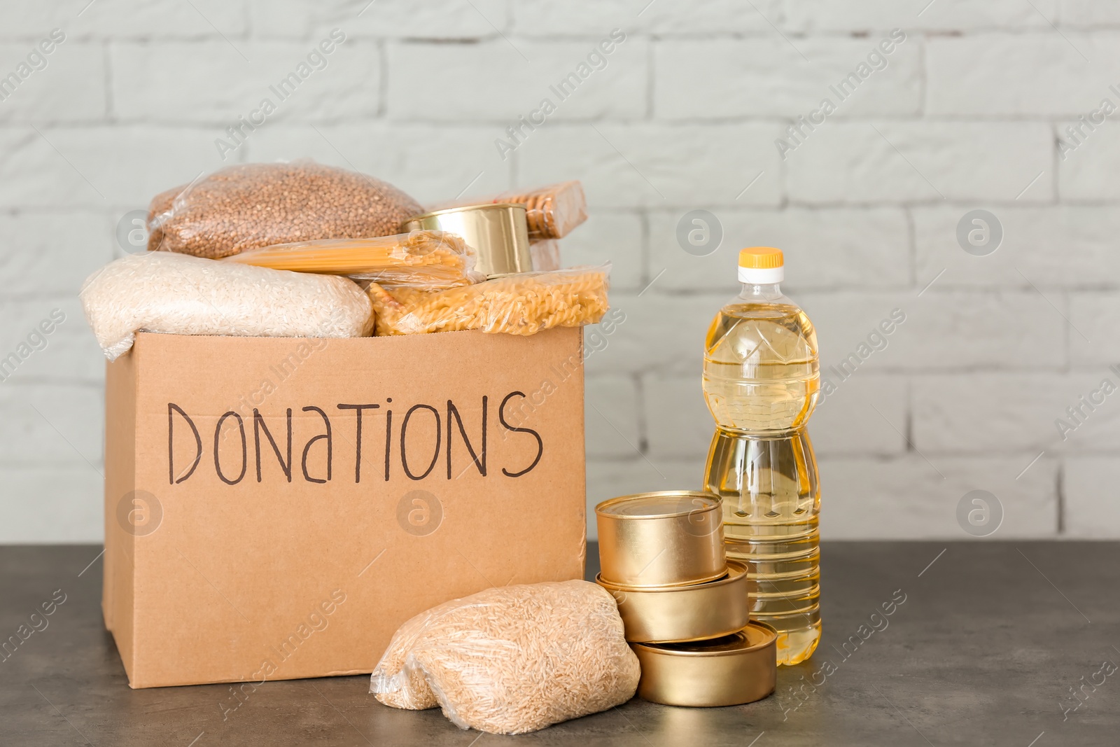 Photo of Donation box with food on table against brick wall