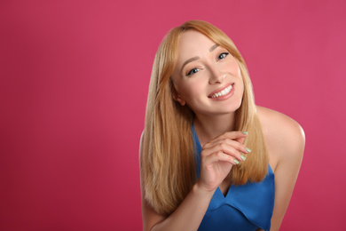 Beautiful young woman with blonde hair on pink background