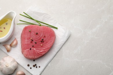 Raw tuna fillet and spices on light gray table, flat lay. Space for text