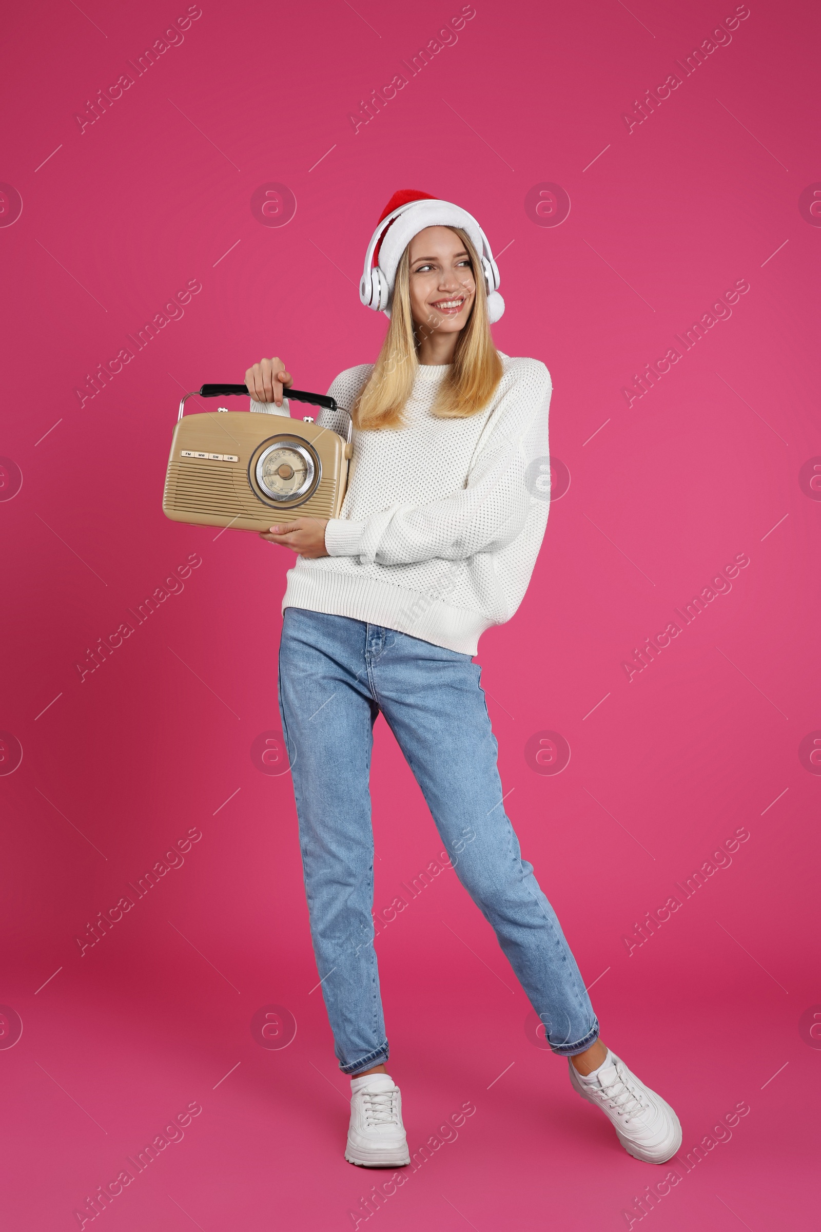 Photo of Happy woman with vintage radio and headphones on pink background. Christmas music