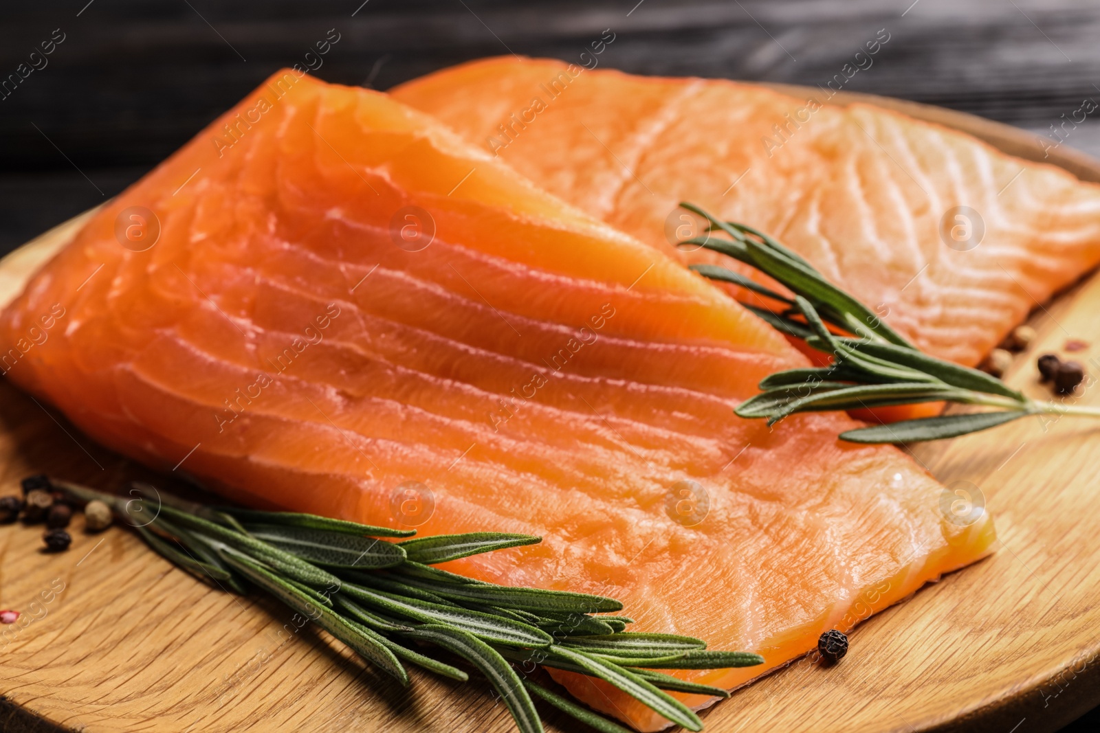 Photo of Wooden plate with tasty salmon fillet on table, closeup
