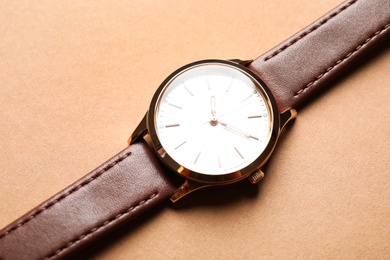 Photo of Luxury wrist watch on beige background, closeup