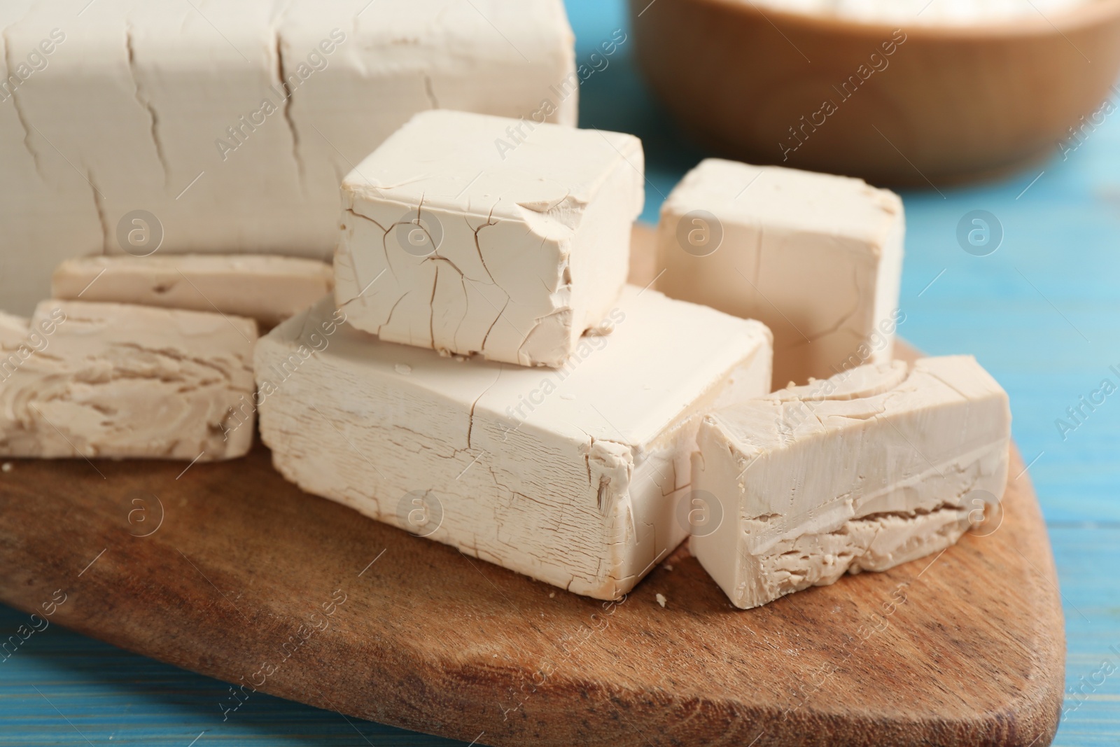 Photo of Pieces of compressed yeast on wooden board, closeup