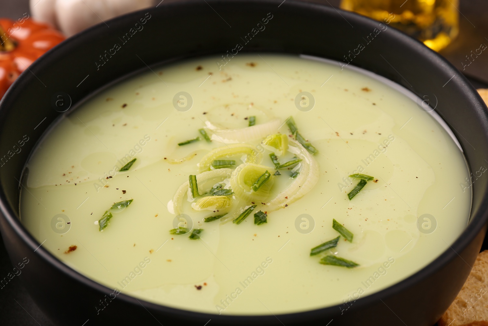 Photo of Bowl of tasty leek soup on table, closeup