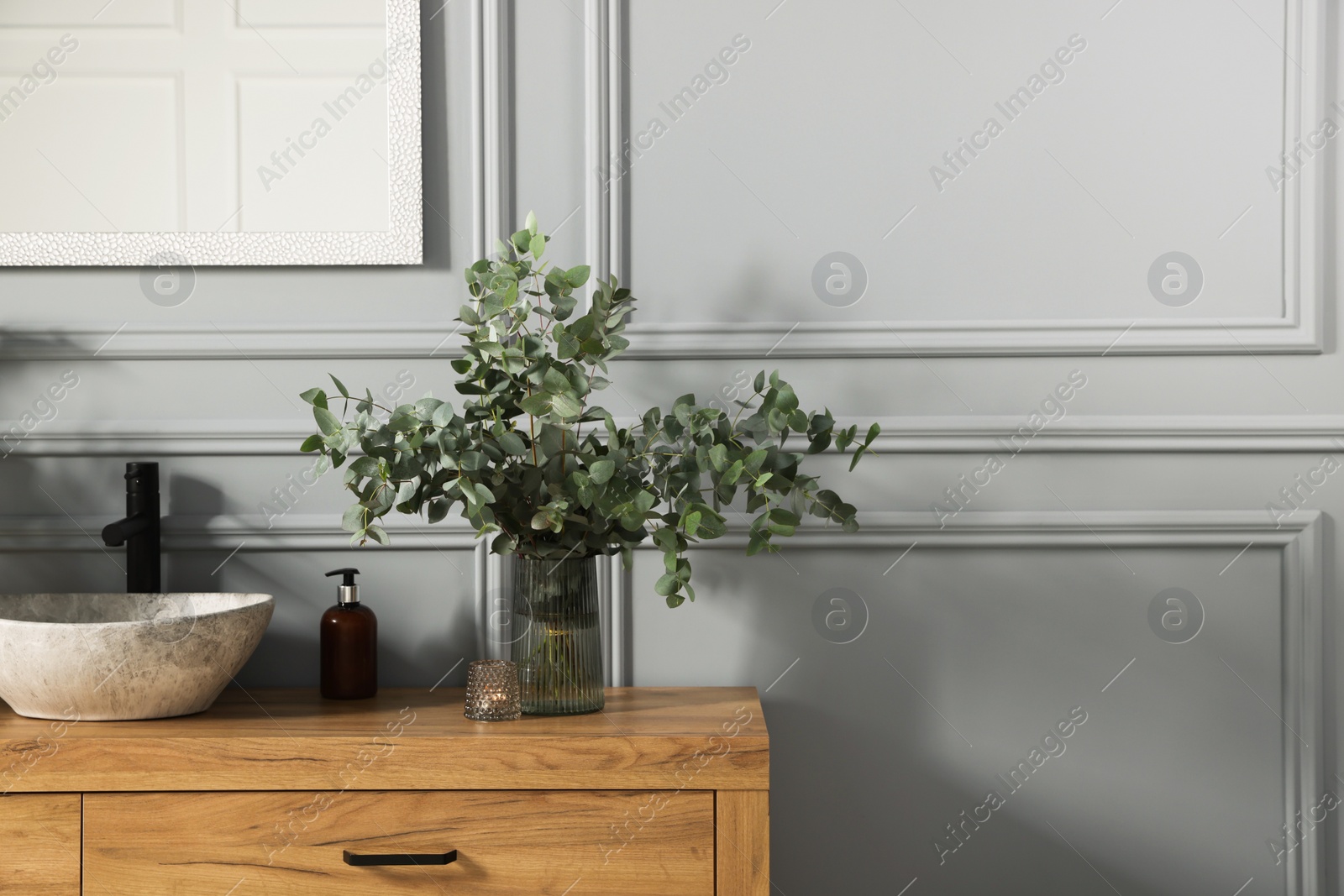 Photo of Stylish vessel sink and eucalyptus branches on bathroom vanity near grey wall, space for text. Interior design