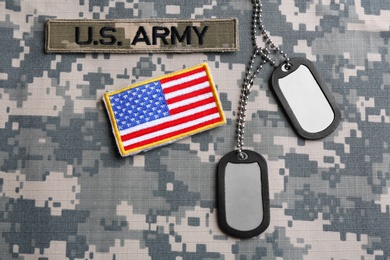 Photo of Military ID tags and US army patches on camouflage background, flat lay