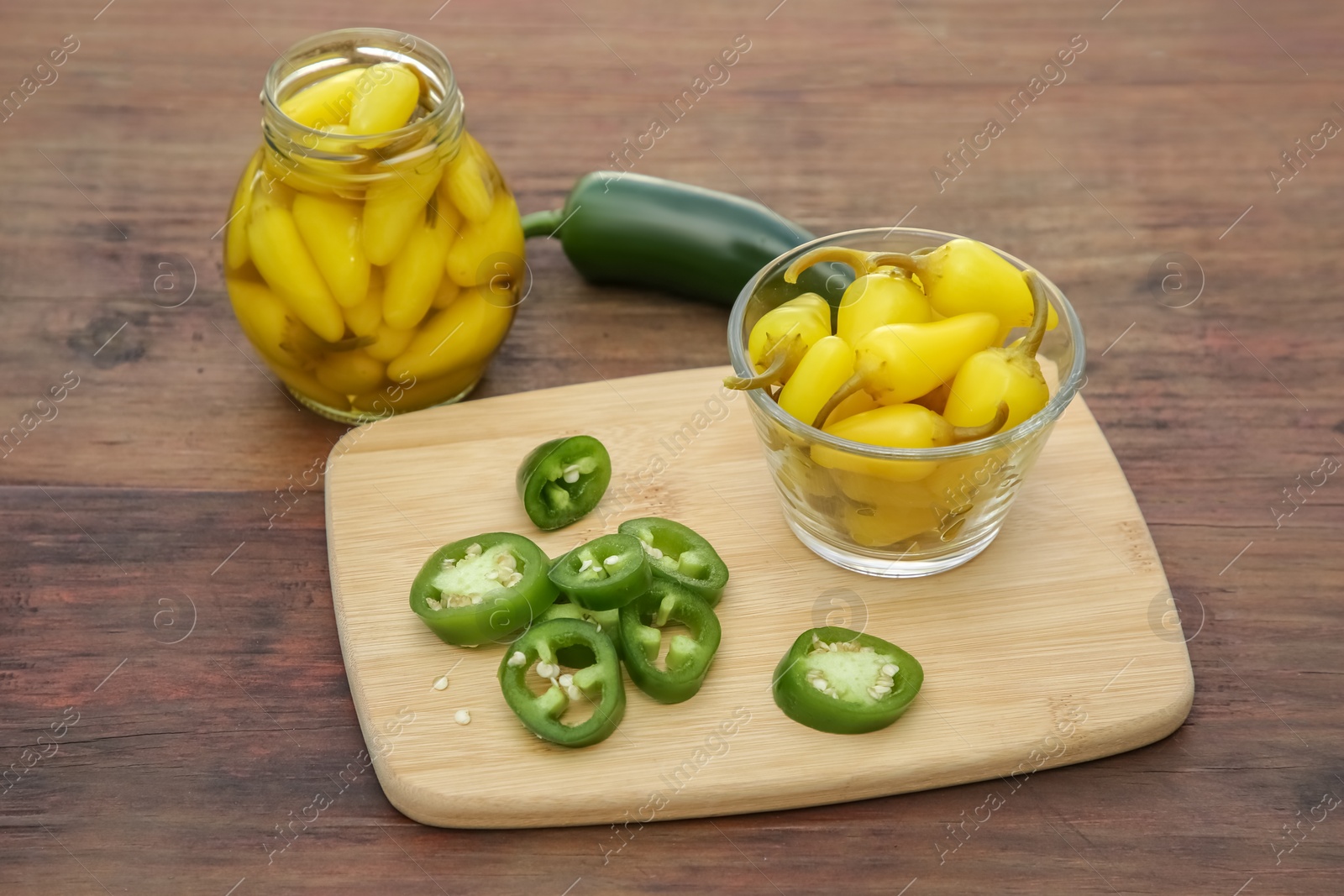 Photo of Fresh and pickled jalapeno peppers on wooden table