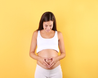 Photo of Happy pregnant woman posing on color background