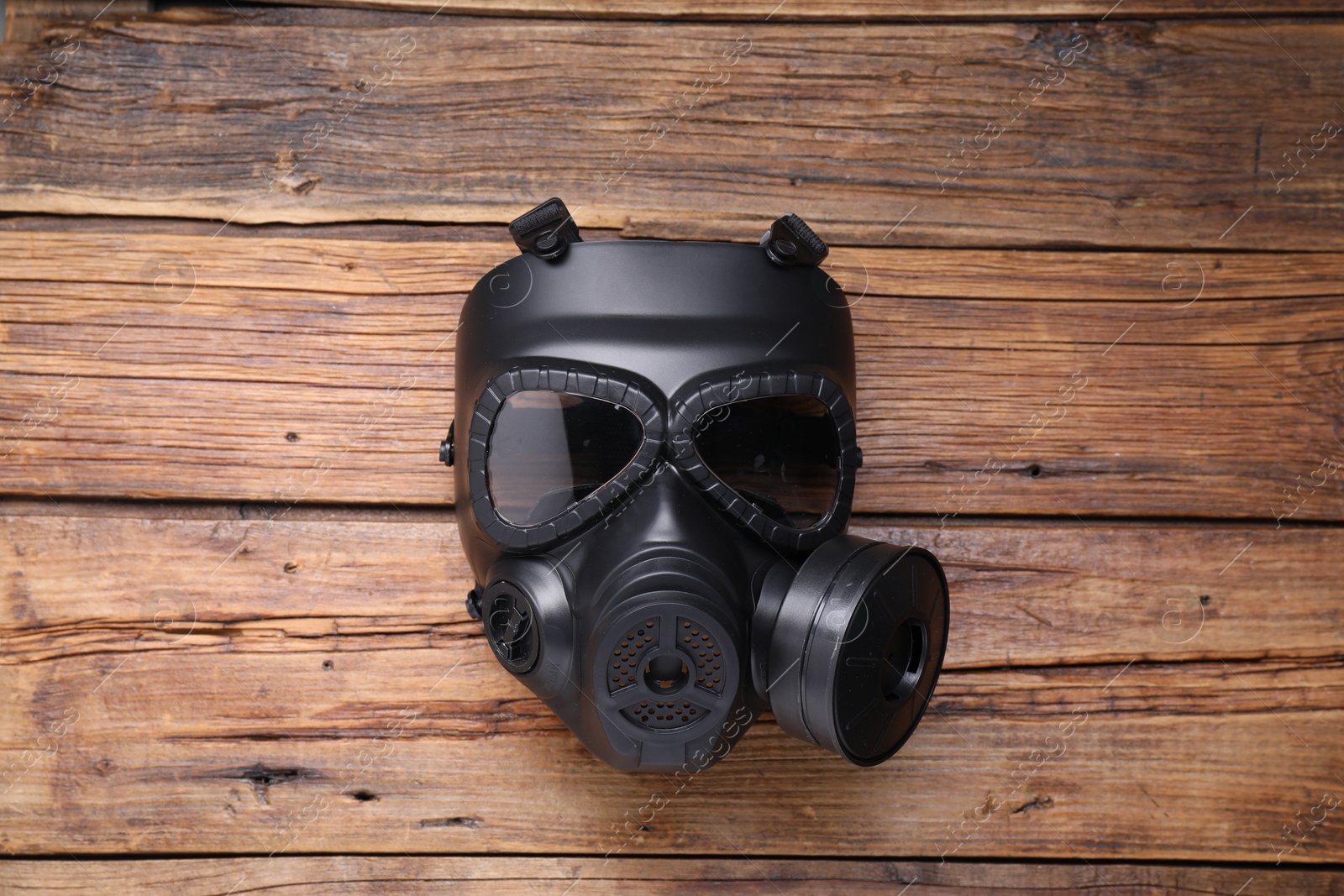 Photo of One gas mask on wooden background, top view