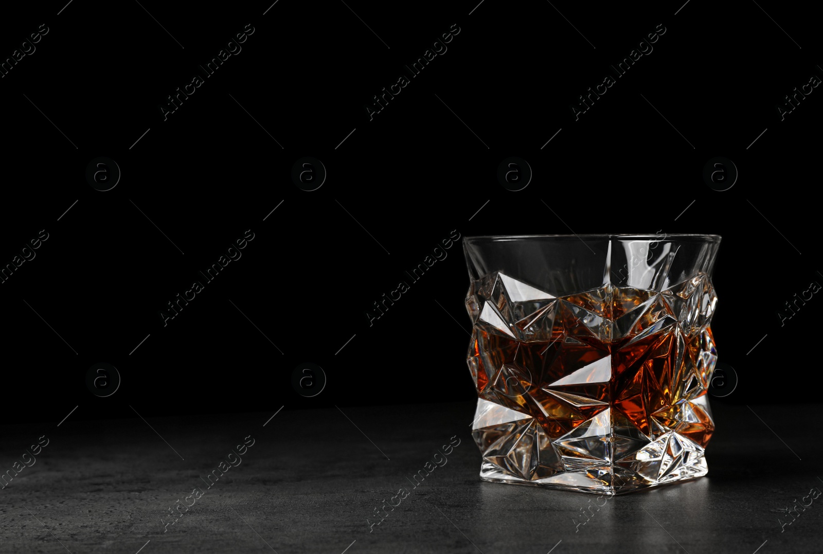 Photo of Golden whiskey in glass with ice cubes on table. Space for text