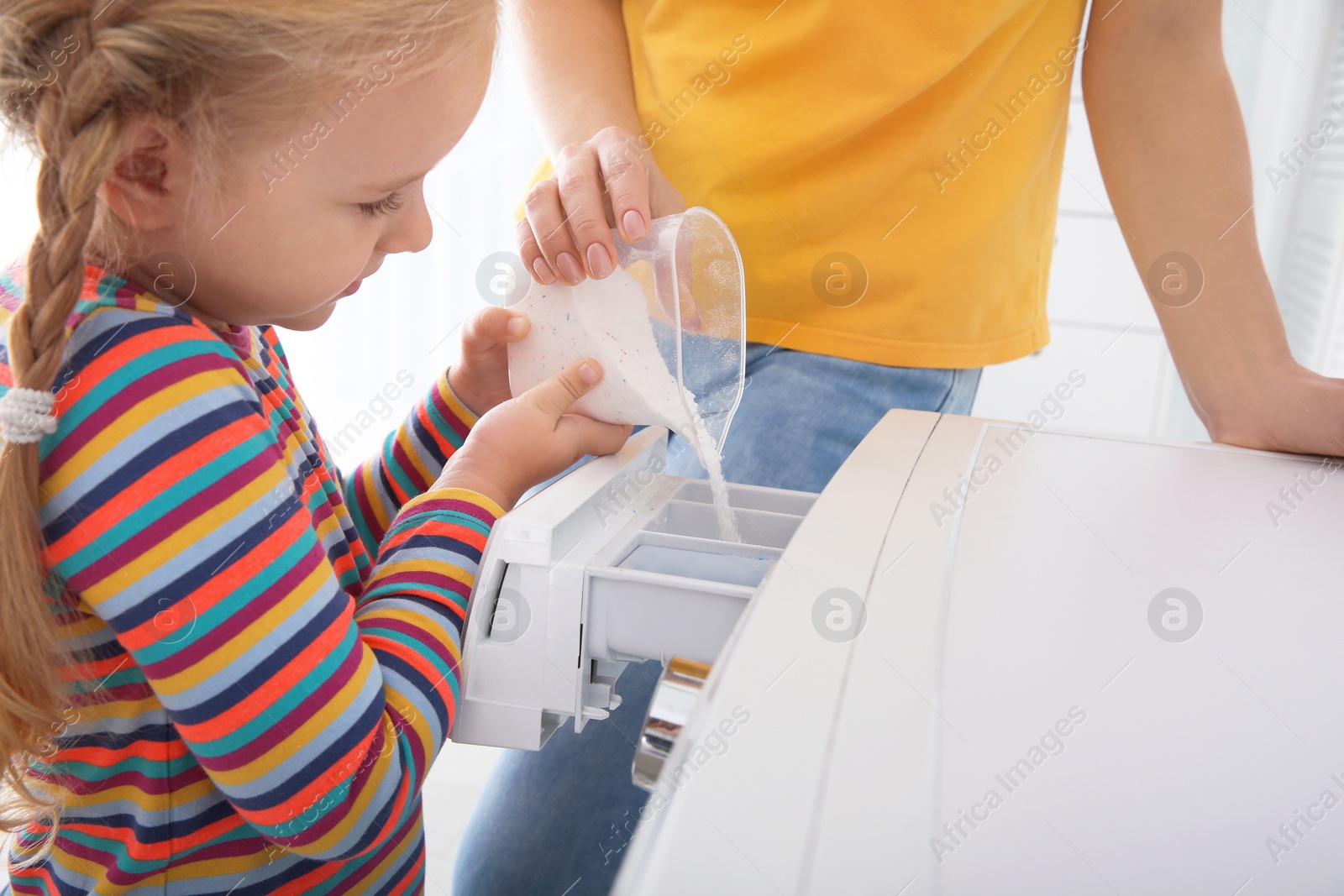 Photo of Little girl helping her mother to do laundry, closeup