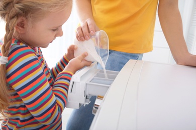 Photo of Little girl helping her mother to do laundry, closeup