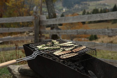 Photo of Cooking delicious vegetables on metal grid for barbecue outdoors