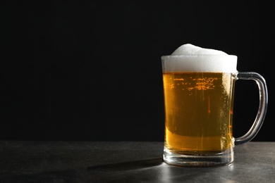 Cold tasty beer on grey table against dark background. Space for text