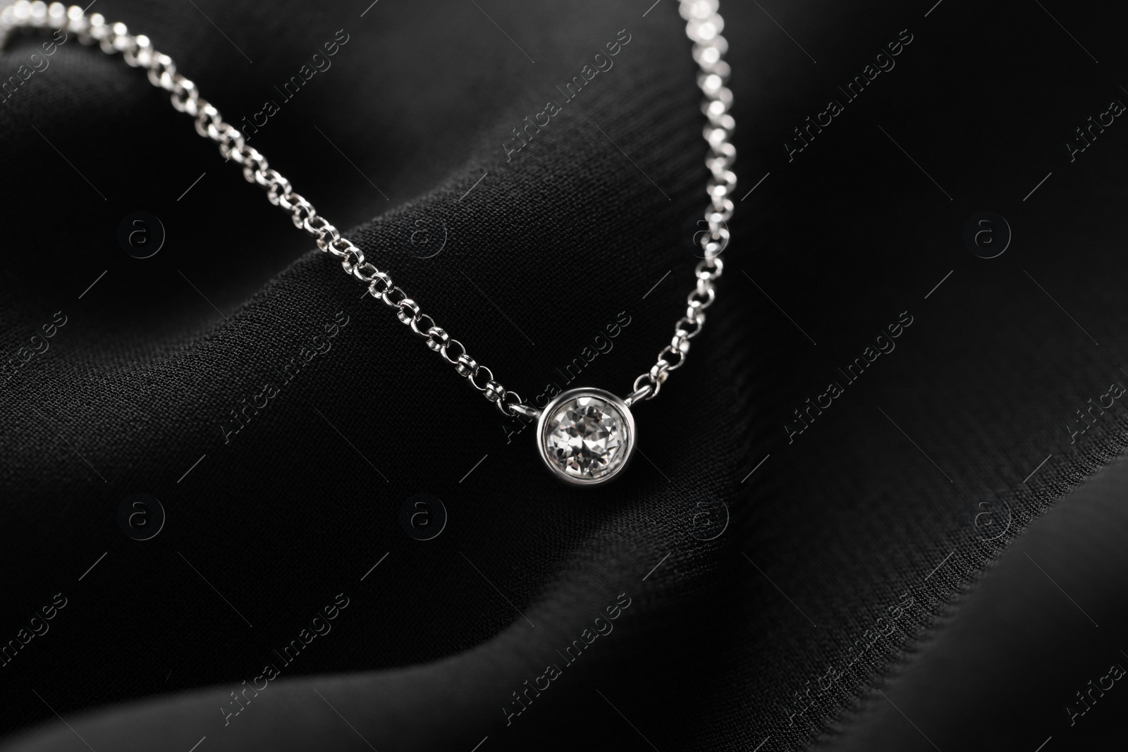 Photo of Beautiful necklace with gemstone on black fabric. Luxury jewelry