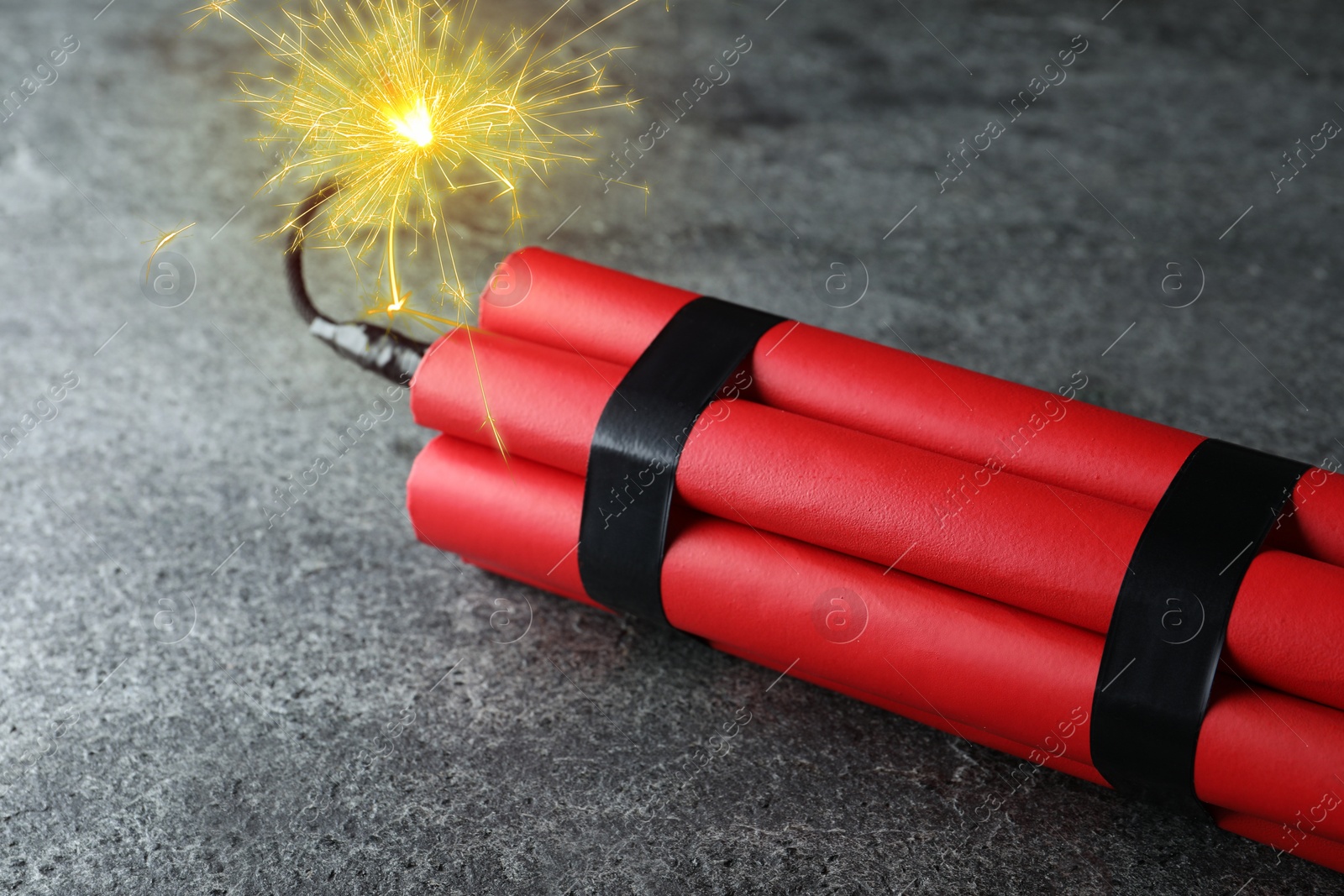 Image of Dynamite bomb with lit fuse on grey table