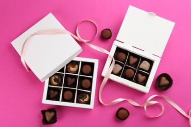 Photo of Different delicious chocolate candies in boxes on pink background, flat lay