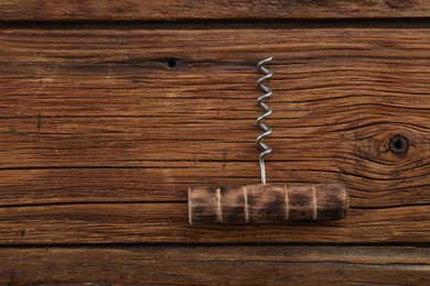 One corkscrew on wooden table, top view. Space for text