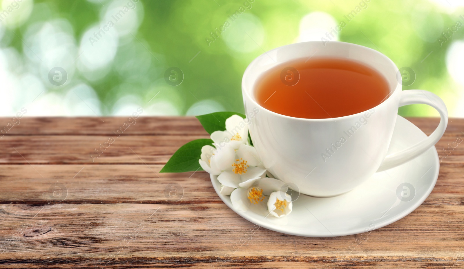 Image of Cup of jasmine tea and fresh flowers on wooden table outdoors, space for text. Banner design