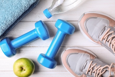 Flat lay composition with vinyl dumbbells and sneakers on wooden background