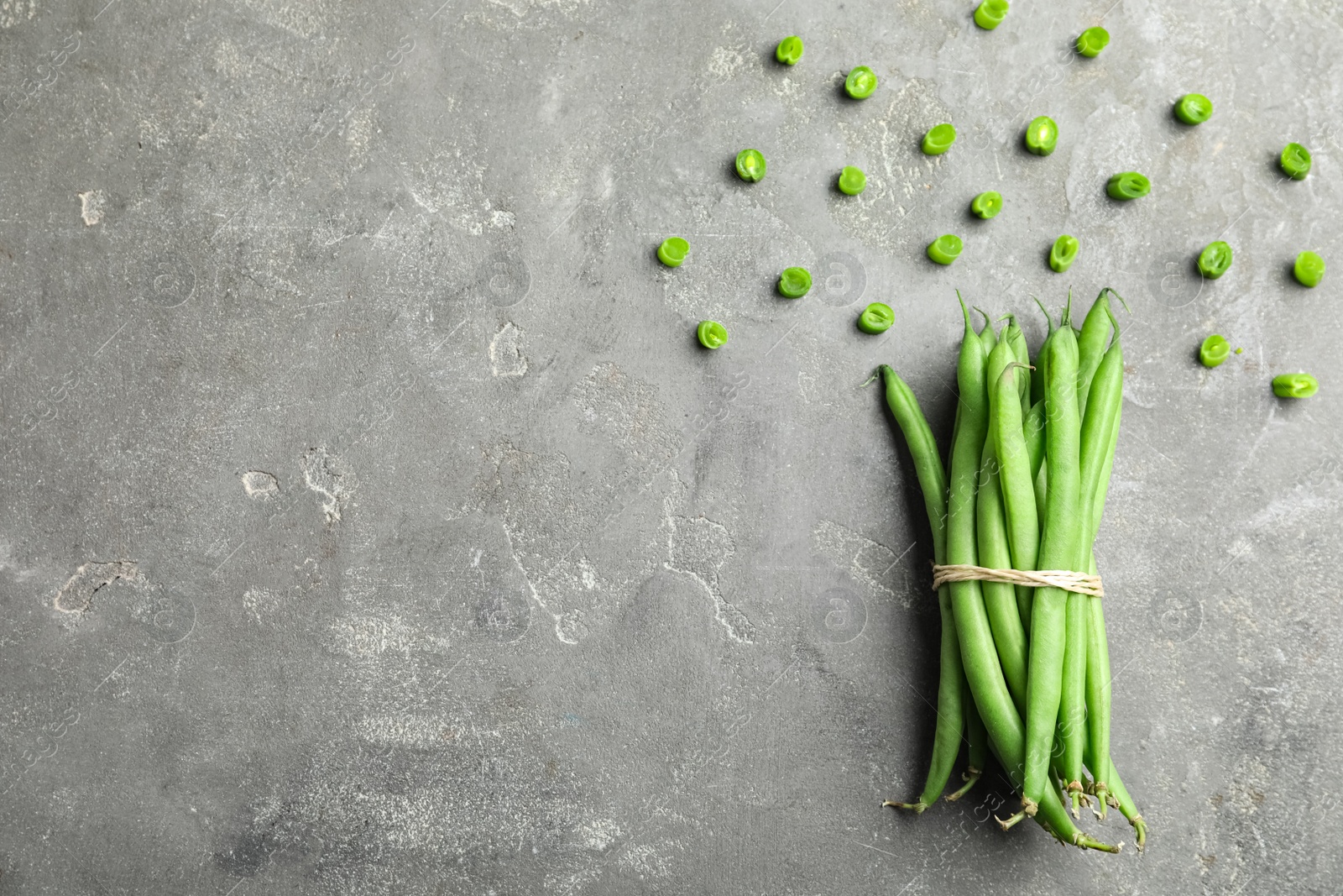 Photo of Flat lay composition with fresh green beans on grey table. Space for text