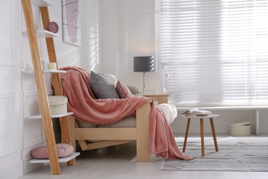 Modern living room interior with comfortable sofa and pink blanket