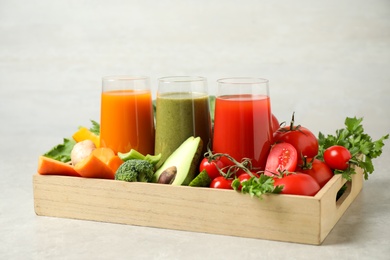Delicious vegetable juices and fresh ingredients on light grey table