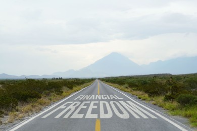 Image of Way to financial freedom. Words on asphalt road