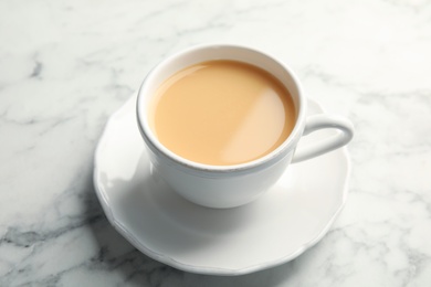 Photo of Cup with black tea and milk on marble table