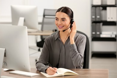 Photo of Hotline operator with headset and notebook working in office