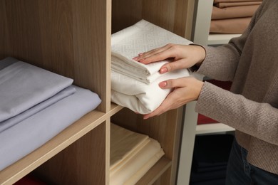 Photo of Woman taking stack of bed linens in shop, closeup