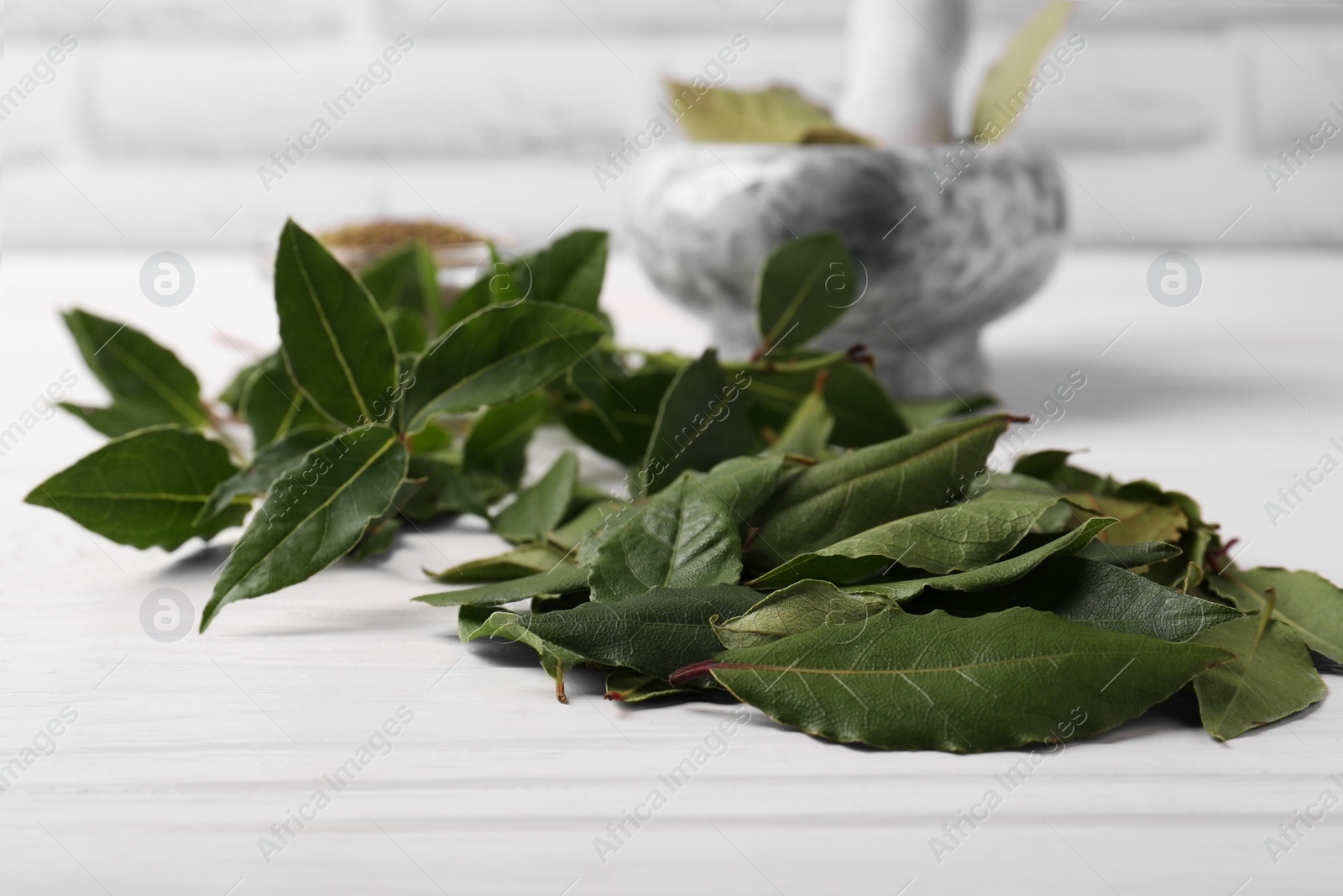 Photo of Fresh green bay leaves on white wooden table, closeup