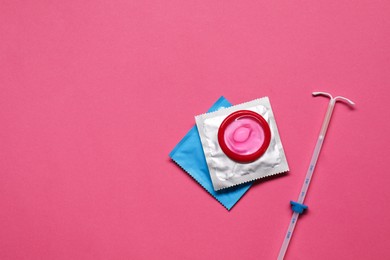 Contraception choice. Condoms and intrauterine device on magenta background, flat lay. Space for text