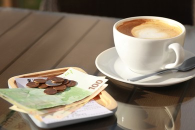 Photo of Tasty hot coffee and payment for order on table. Leave tip