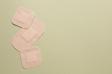 Photo of Different contraceptive patches on green background, flat lay. Space for text