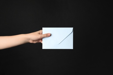 Photo of Woman holding white paper envelope on black background, closeup