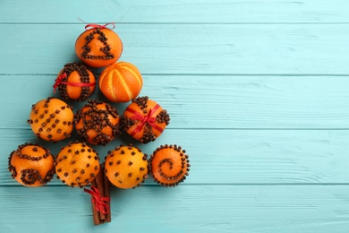 Photo of Flat lay composition with pomander balls made of fresh tangerines and cloves on light blue wooden table, space for text