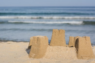 Photo of Beautiful sand castle on beach near sea. Space for text