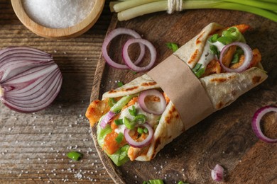 Photo of Delicious pita wrap with meat and vegetables on wooden table, flat lay