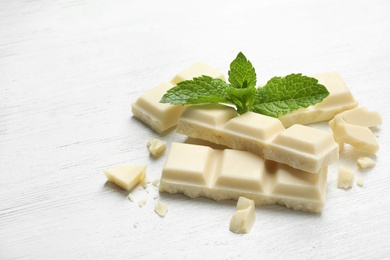 Photo of Pieces of white chocolate with mint on light table