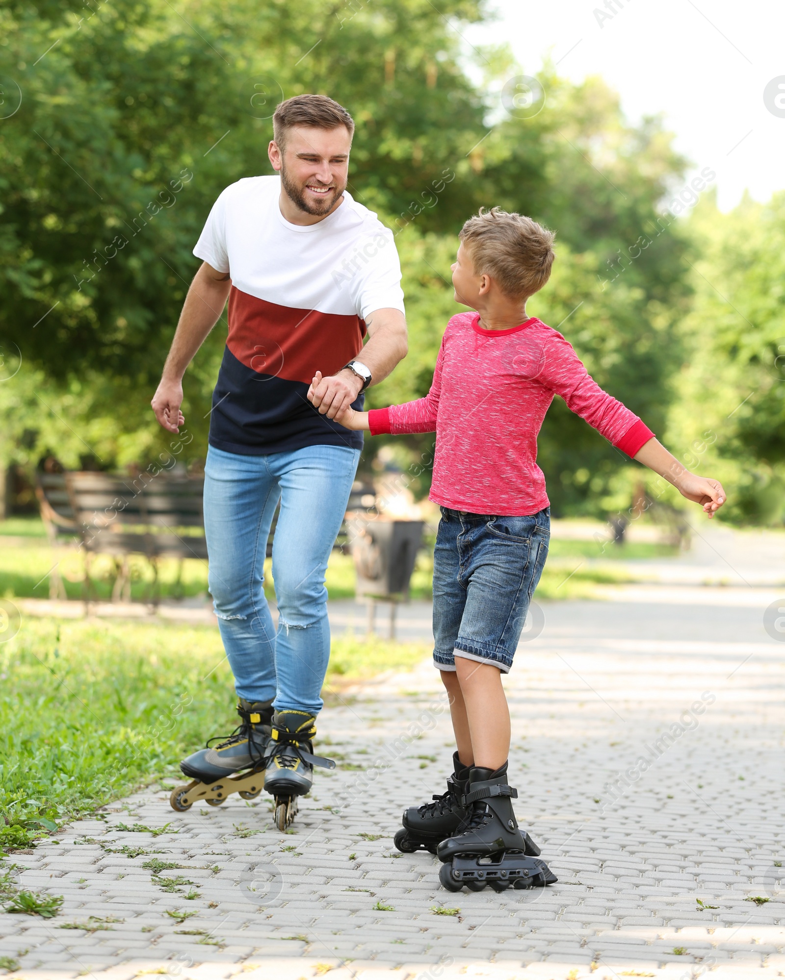 Photo of Father and son roller skating in summer park