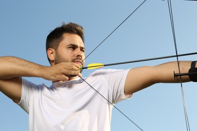 Photo of Man with bow and arrow practicing archery outdoors