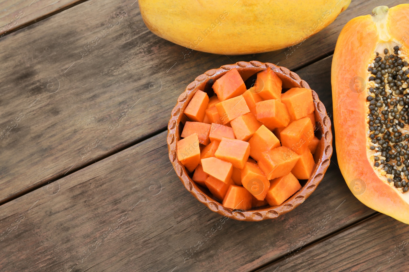 Photo of Tasty cut and whole papaya fruits on wooden table, flat lay. Space for text