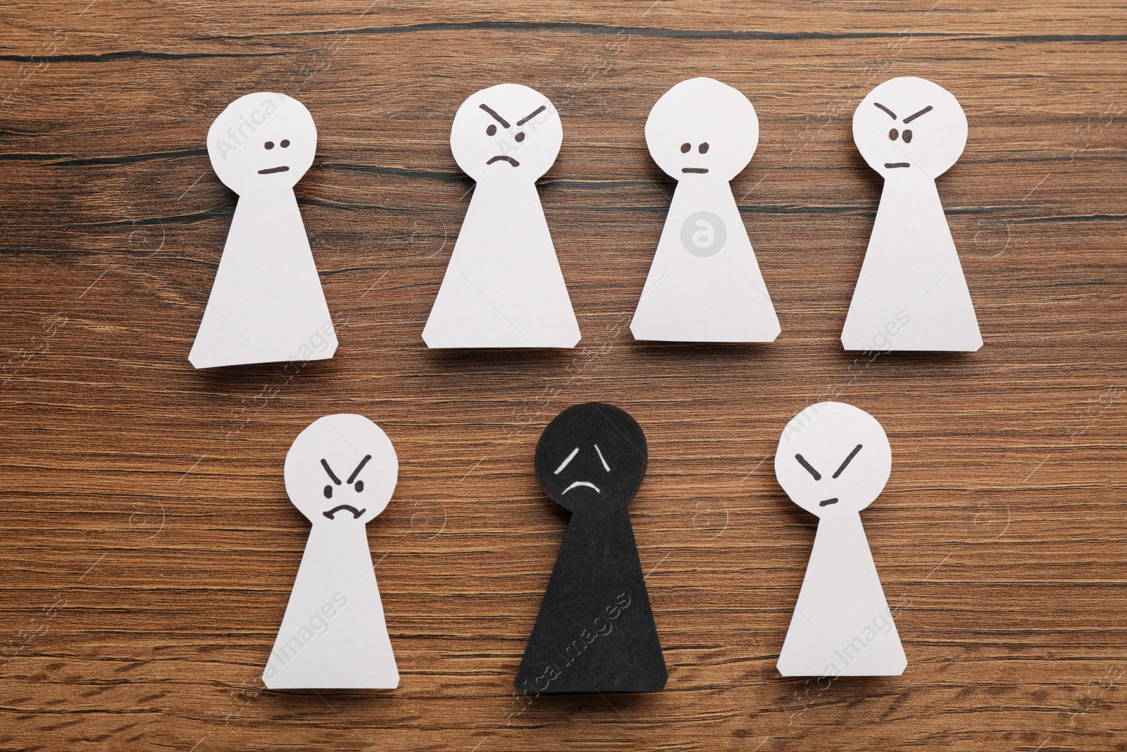 Photo of Flat lay composition with black and white paper figures on wooden table. Racism concept