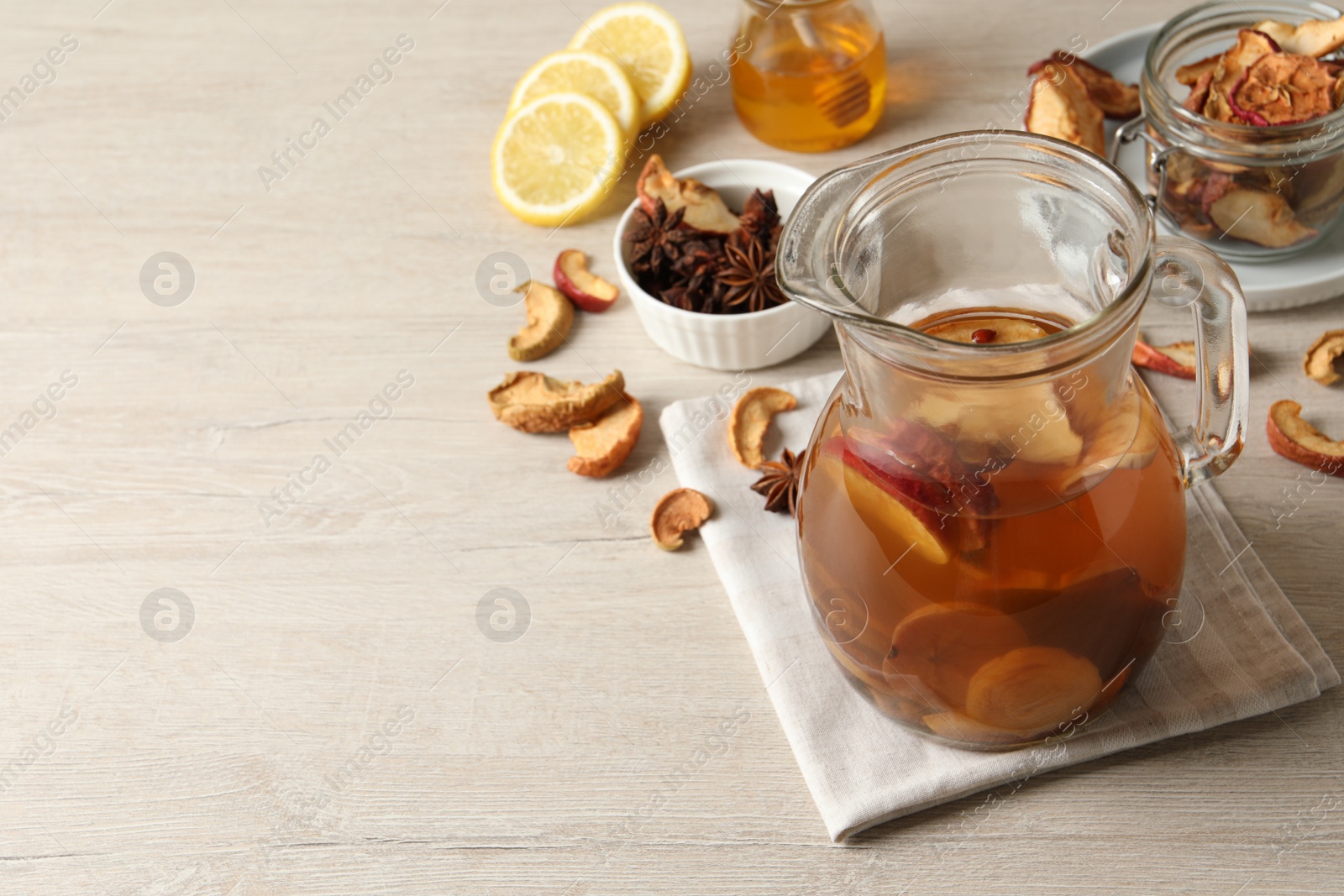 Photo of Delicious compote with dried fruits in glass jug on light wooden table, space for text